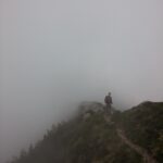 Ein Mann auf einem Berg vor einer Nebelwand